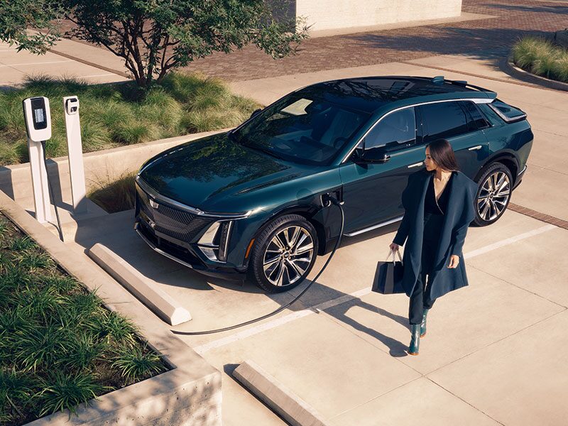 A Business Women Walking Away From a 2025 Cadillac LYRIQ Charging at a Public Charger