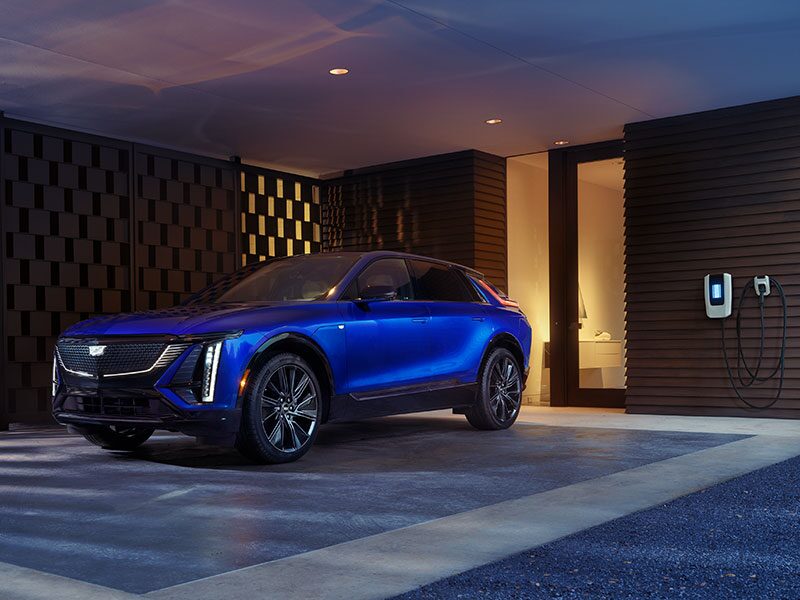 The Side Profile of a Blue 2025 Cadillac LYRIQ Charging and Parked in a Luxurious Garage