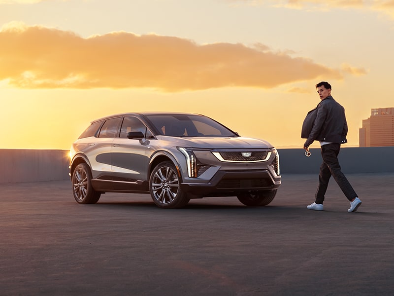 A Man Walking Towards a 2026 Cadillac OPTIQ Parked Outside