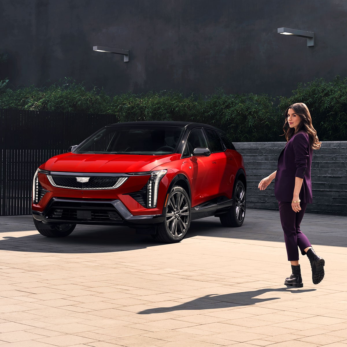 A Woman Walking Towards a Parked, Red 2026 Cadillac OPTIQ