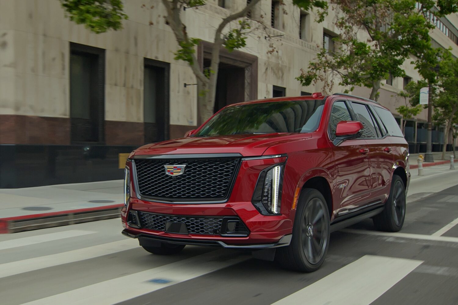 Side View of a Red 2026 Cadillac Escalade-V Driving Through a Road Downtown